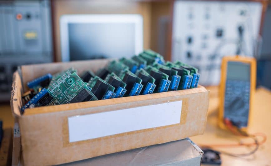 Des microcircuits intégrés verts en gros plan sont empilés dans une boîte pour se préparer à la suite en usine pour la production d'équipements